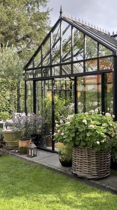 a greenhouse with many plants in it and lots of flowers growing inside the house on the lawn