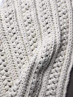 a white crocheted blanket laying on top of a bed