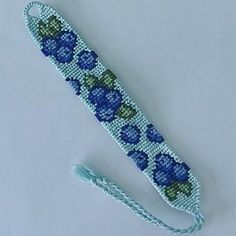 a beaded bracelet with blue flowers on it and a tassel hanging from the end