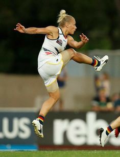 a woman is jumping in the air to catch a frisbee with her legs