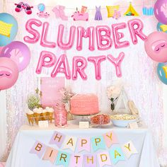 a table topped with lots of balloons next to a sign that says slumber party