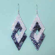 a pair of earrings made out of beads on a blue background with white and black squares