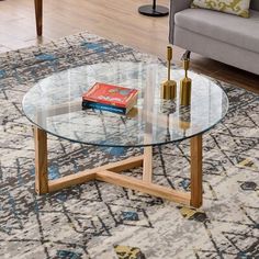 a glass table with two books on it in a living room next to a couch