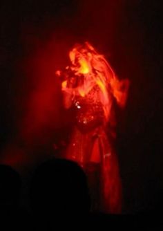 a woman with long hair standing in front of a red and black light at night