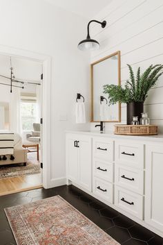 a bathroom with white cabinets and black flooring is seen in this image from the doorway