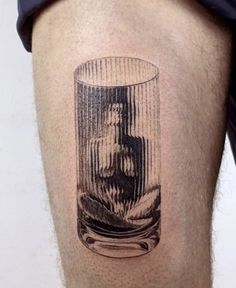 a man's leg with a tattoo on it that has a glass in it