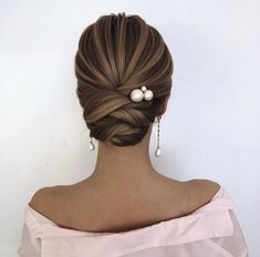 a woman with her hair in a low bun and two pearls on the back of her head