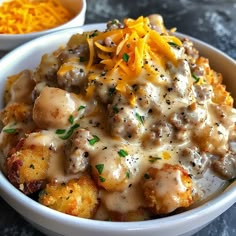 a white bowl filled with potatoes covered in gravy and topped with cheddar cheese