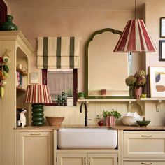 a kitchen with white cabinets and striped lamps on the wall above the sink is decorated in green and red