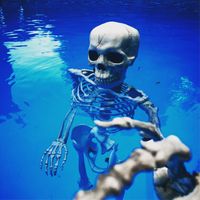 a skeleton floating in the water with its hands extended out to touch it's body