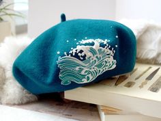 Introducing our Embroidered Ocean Waves Teal Color Wool Beret! Dive into the world of cozy fashion with this beautifully crafted accessory. Made from soft and warm wool, it is perfect for keeping you stylishly snug during those chilly days. The intricate embroidery of ocean waves adds a touch of serenity and whimsy to the beret, making it a unique and eye-catching piece. The rich teal color is both vibrant and versatile, complementing any outfit effortlessly. Whether you're strolling along the b Ocean Clothing, Embroidered Beret, Ocean Outfits, Ocean Fashion, Wool Beret, Wool Berets, Embroidered Hat, Hat For Women, Beret Hat