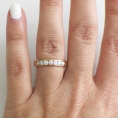 a woman's hand with a gold ring and diamond band on her left finger