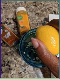 a person holding an orange in their hand next to some other food and condiments