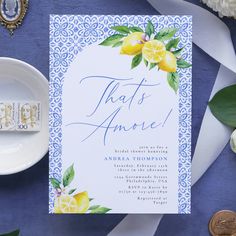 a blue and white wedding card with lemons on it, next to some flowers