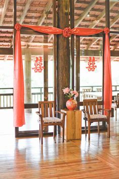 the chairs are set up with red sashes and flowers in vases on them