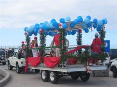 a truck with balloons on the back driving down a street