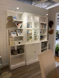 a white bookcase with many books on it in a living room next to a dining room table