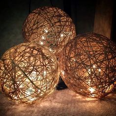 three balls with lights on them sitting next to each other in front of a purple frame