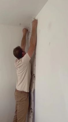 a man that is standing up against a wall with his hands on the edge of it