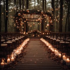 an outdoor wedding setup with candles and lanterns on the aisle, surrounded by trees in the background