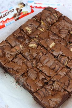 a chocolate brownie sitting on top of a white plate next to a candy bar