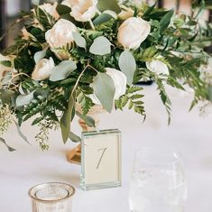 there is a vase with flowers and greenery on the table at this wedding reception