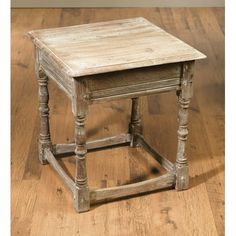 an old wooden side table sitting on top of a hard wood floor with no one around it