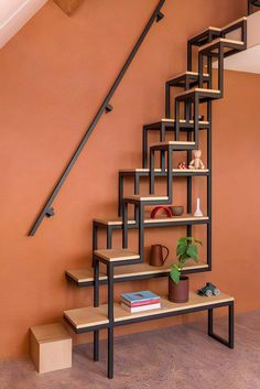 a set of stairs in an orange room with bookshelf and plant on it