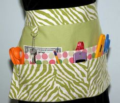 a woman's apron with scissors and other items in the pocket on her waist