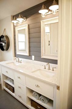 a bathroom with two sinks, mirrors and lights on the wall above them is shown