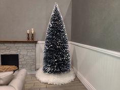 a blue christmas tree sitting in the corner of a living room next to a fireplace