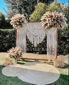 an outdoor wedding ceremony set up with large flowers and tassels on the altar