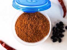 an overhead view of some spices in a small container with chili peppers on the side