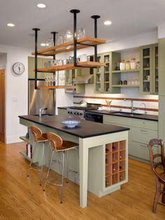 a kitchen with wooden floors and lots of shelves on the wall next to an island