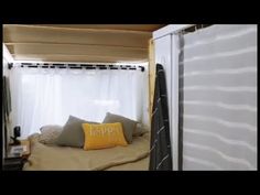 the interior of a camper trailer with curtains and pillows