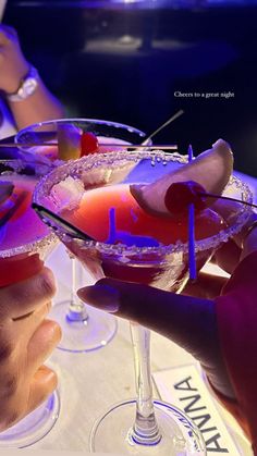 two people are holding up martinis in their hands at a party or social gathering