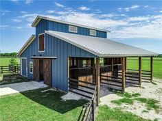 a blue barn with a metal roof and two stalls