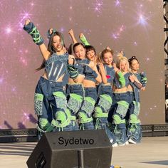 a group of young women standing on top of a stage with their arms in the air