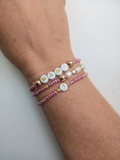 a woman's arm wearing three bracelets with beads and charms on it,