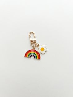 a keychain with a rainbow and two eggs on top of it, sitting on a white surface