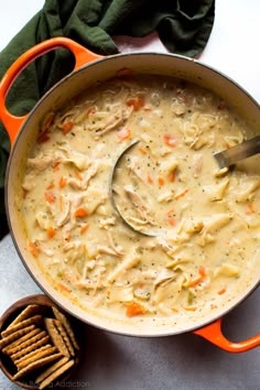 a pot filled with chicken noodle soup next to crackers