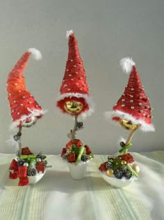 three red and white gnome hats on top of small pots filled with christmas decorations next to each other