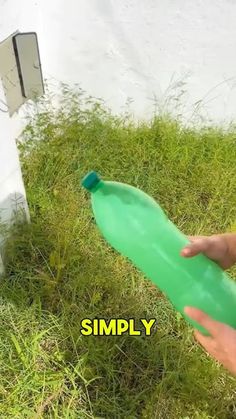 a person holding a green plastic bottle in their hand next to a white wall with the words simply written on it