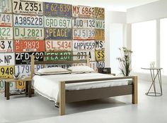 there is a bed with lots of license plates on the wall behind it and a side table next to it