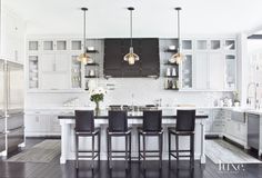 a kitchen with white cabinets and black chairs