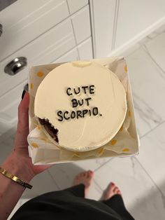 someone holding up a cake that says cute but scorpioo on it in front of their feet