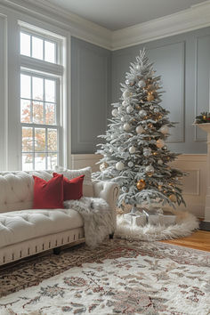 a living room with a white christmas tree in the corner and red pillows on the couch