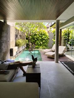 an outdoor living area with couches, tables and a pool in the middle of it