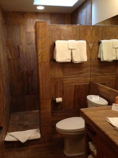 a bathroom with a toilet, sink and mirror in it's center wall is made of wood