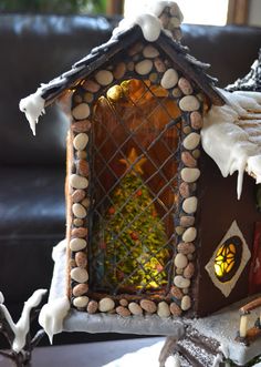 a small house made out of rocks and wood with snow on the ground next to it